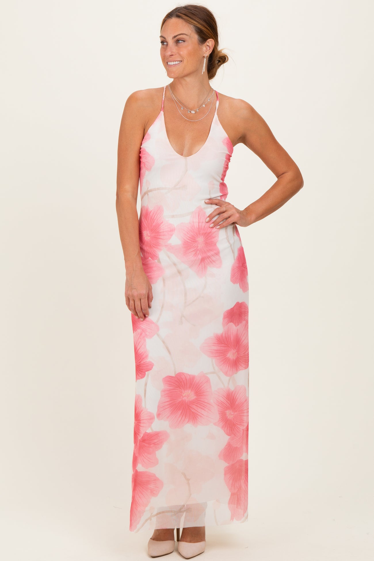 woman wearing a floral maxi dress with pink flowers and a deep v-neckline, styled with heels and jewelry