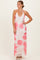 woman wearing a floral maxi dress with pink flowers and a deep v-neckline, styled with heels and jewelry