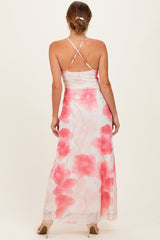 woman wearing a backless floral maxi dress with pink flowers and a crisscross strap detail