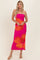 woman wearing a bright pink strapless maxi dress with large orange hibiscus flowers