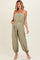 woman wearing a strapless olive green maternity jumpsuit with a drawstring waist and gathered ankle cuffs, showcasing a baby bump