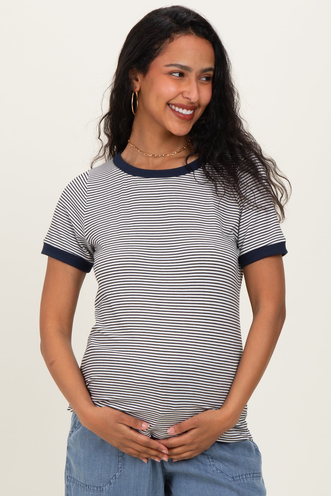 woman wearing a navy and white striped maternity top and holding her baby bump