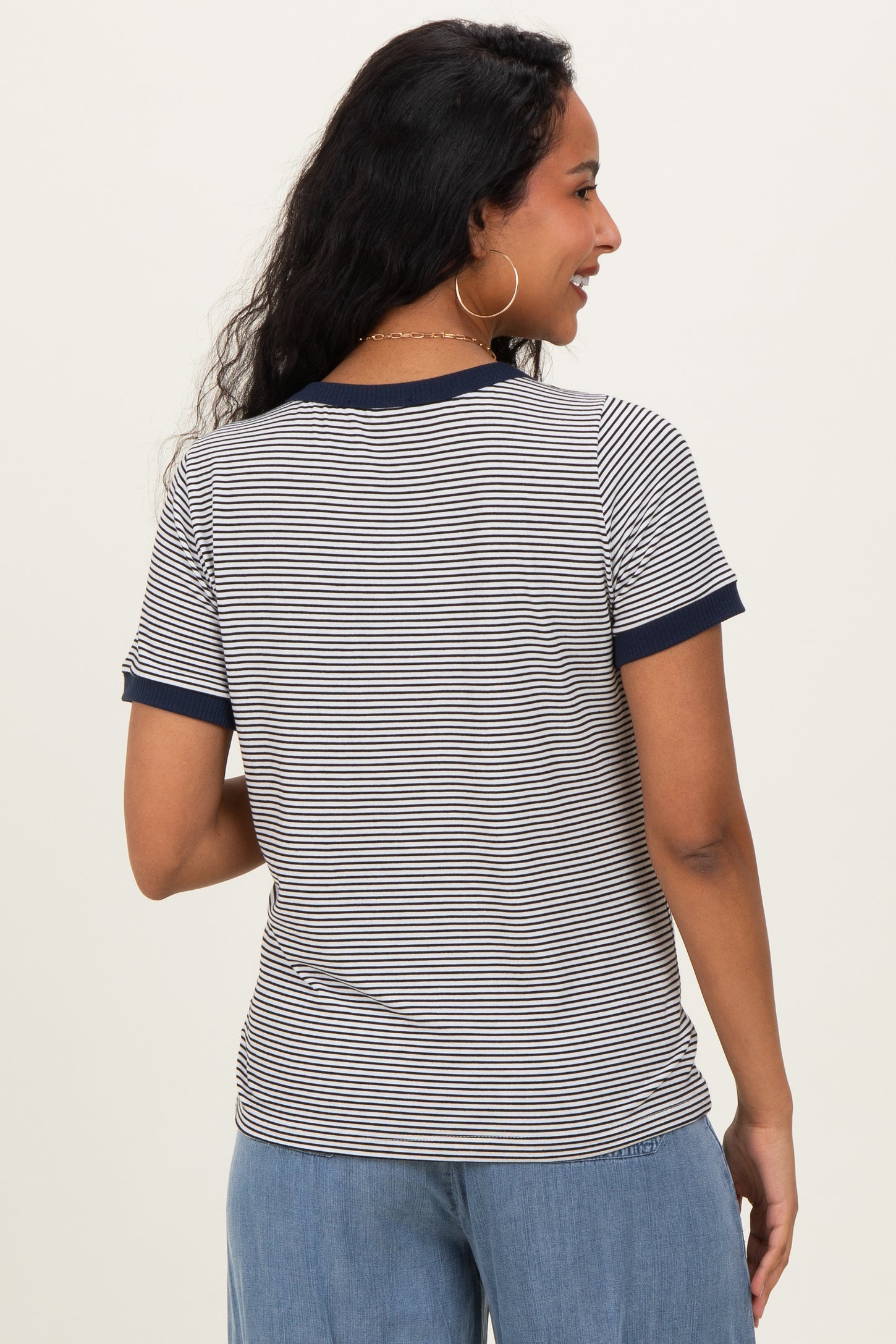 woman wearing a navy and white striped maternity t-shirt with contrast sleeves, showing a relaxed fit from the back