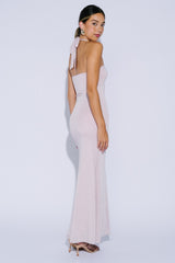 woman wearing a light pink fitted strapless gown with a bow detail on the back and a flared hem