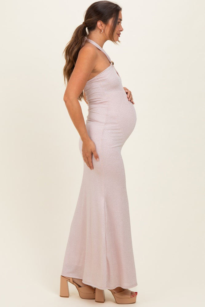 woman wearing a blush pink halter neck maternity gown with a fitted silhouette, showcasing her baby bump