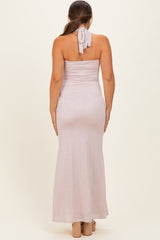 woman wearing a light pink maternity dress with a strapless design and a bow at the back