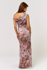 woman wearing a one-shoulder floral maxi dress in shades of pink and beige, showing a fitted silhouette from the back
