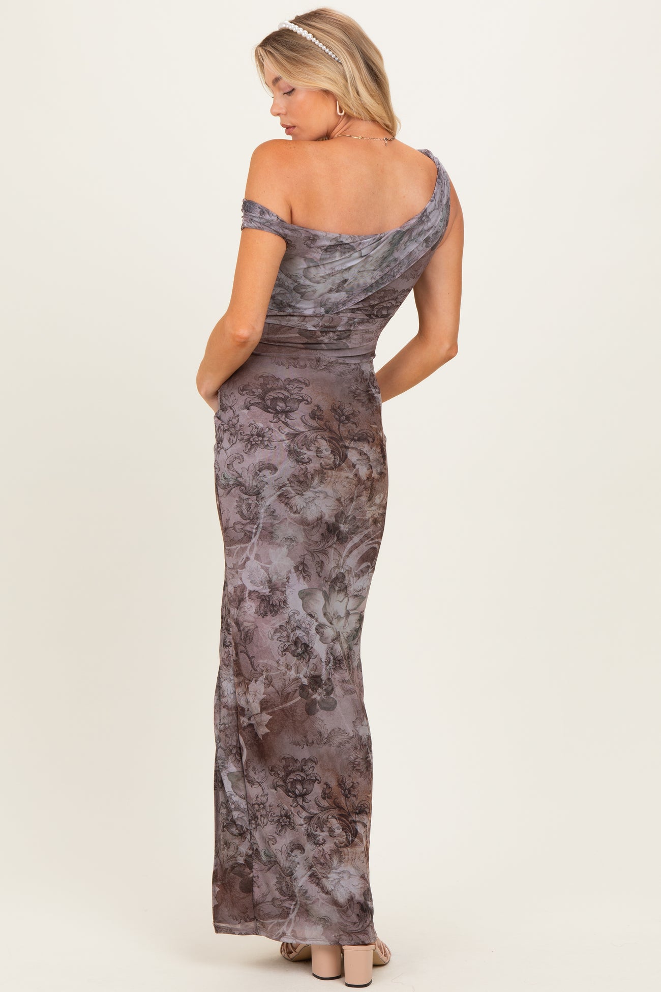 woman wearing a floral off-the-shoulder maternity gown with a fitted silhouette and flowing skirt, showing her back