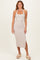 woman wearing a taupe halter neck midi dress with a side slit and platform sandals