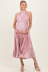 woman wearing a pink floral maternity dress with pleats and a halter neck, showing her baby bump