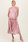 woman wearing a pink floral maternity dress with pleats and a halter neck, showing her baby bump