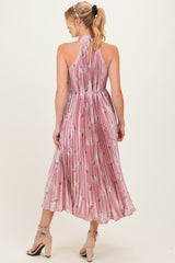 woman wearing a pink floral pleated maternity dress with a halter neckline and a flowing midi skirt