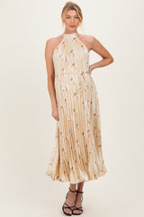 woman wearing a cream floral pleated maternity dress with a halter neck and cinched waist, showing a baby bump