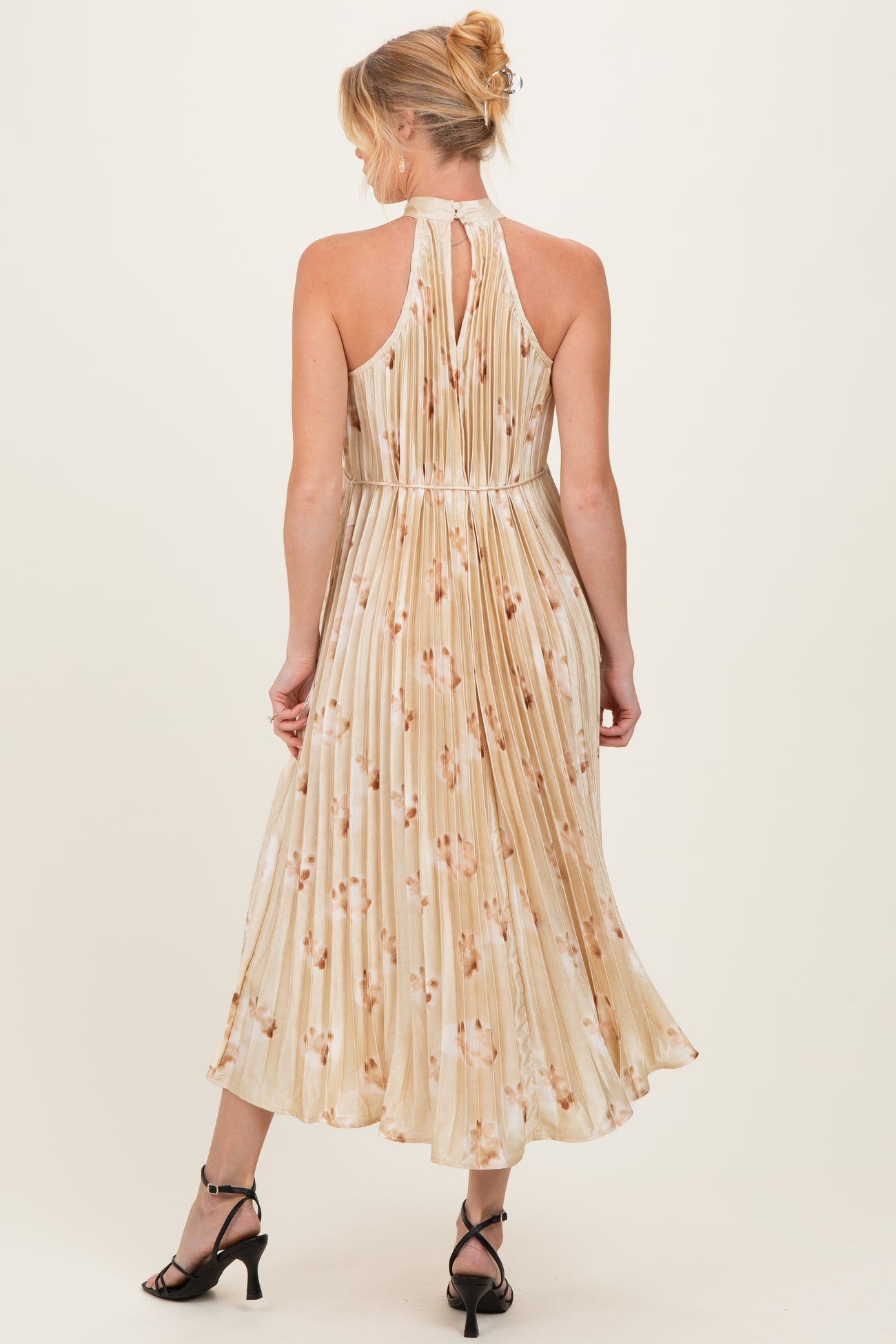 woman wearing a floral print maternity dress with a halter neckline and pleated skirt, viewed from the back