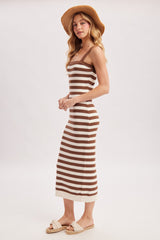 woman wearing a brown and cream striped fitted midi dress with a straw hat and slide sandals