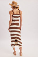 woman wearing a brown and cream striped midi dress with a back slit and a straw hat, facing away from the camera