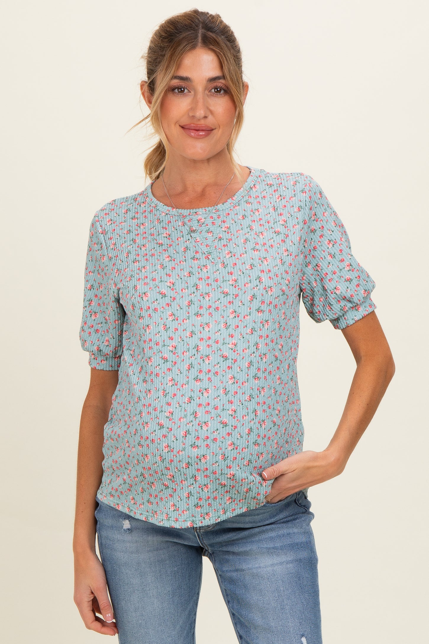 woman wearing a light blue floral maternity top and showing her baby bump