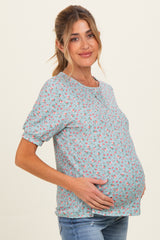 woman wearing a light blue floral maternity top and showing her baby bump
