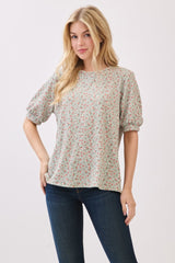 woman wearing a light green puff sleeve top with red floral prints and blue jeans