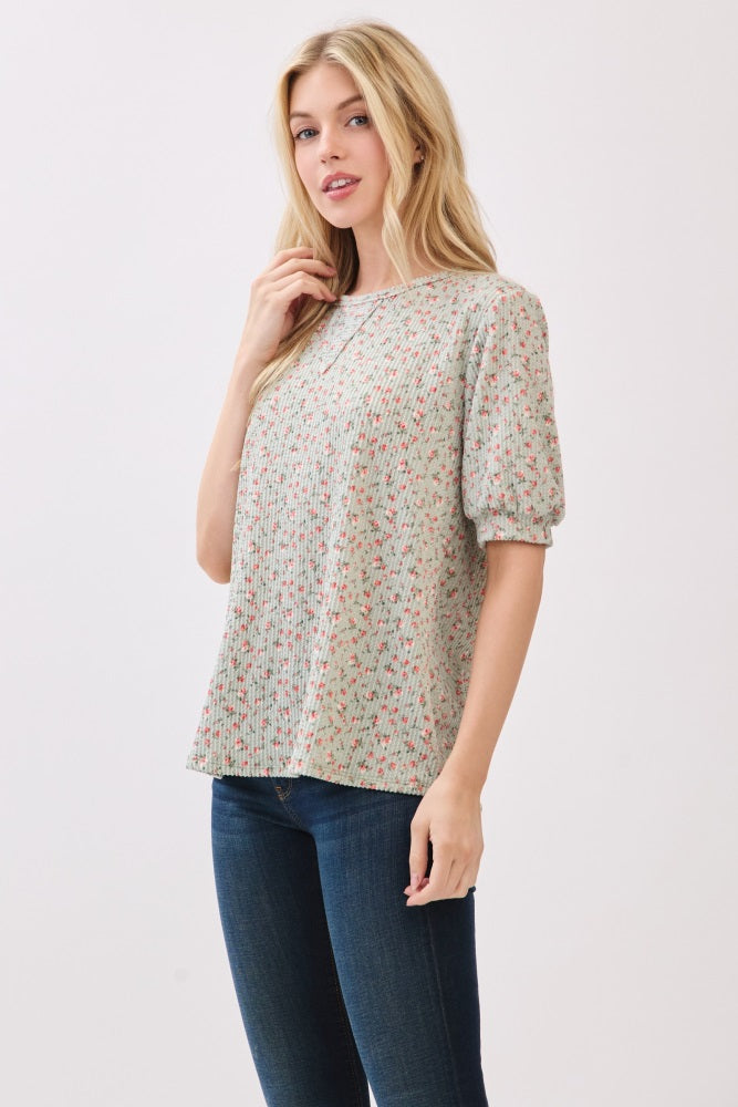 woman wearing a light green floral print short sleeve top with puff sleeves and blue jeans