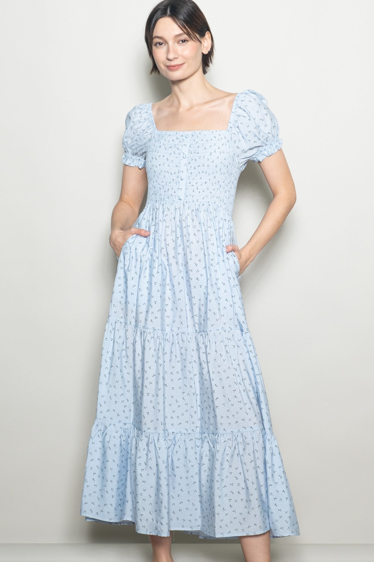 woman wearing a light blue puff sleeve midi dress with a smocked bodice and pockets