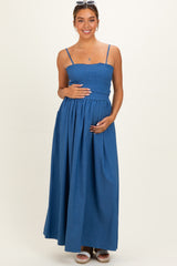 woman wearing a blue maternity maxi dress with a smocked bodice and holding her baby bump