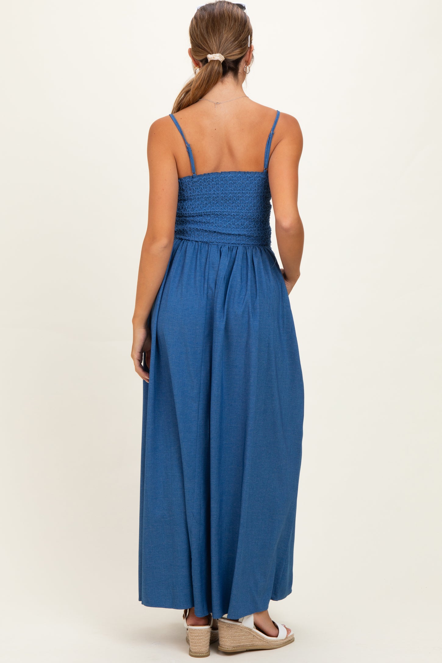 woman wearing a blue maternity maxi dress with adjustable straps and smocked bodice, showing a baby bump from the back