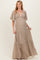 woman wearing a beige v-neck maxi maternity dress with flutter sleeves and tiered skirt, showing her baby bump