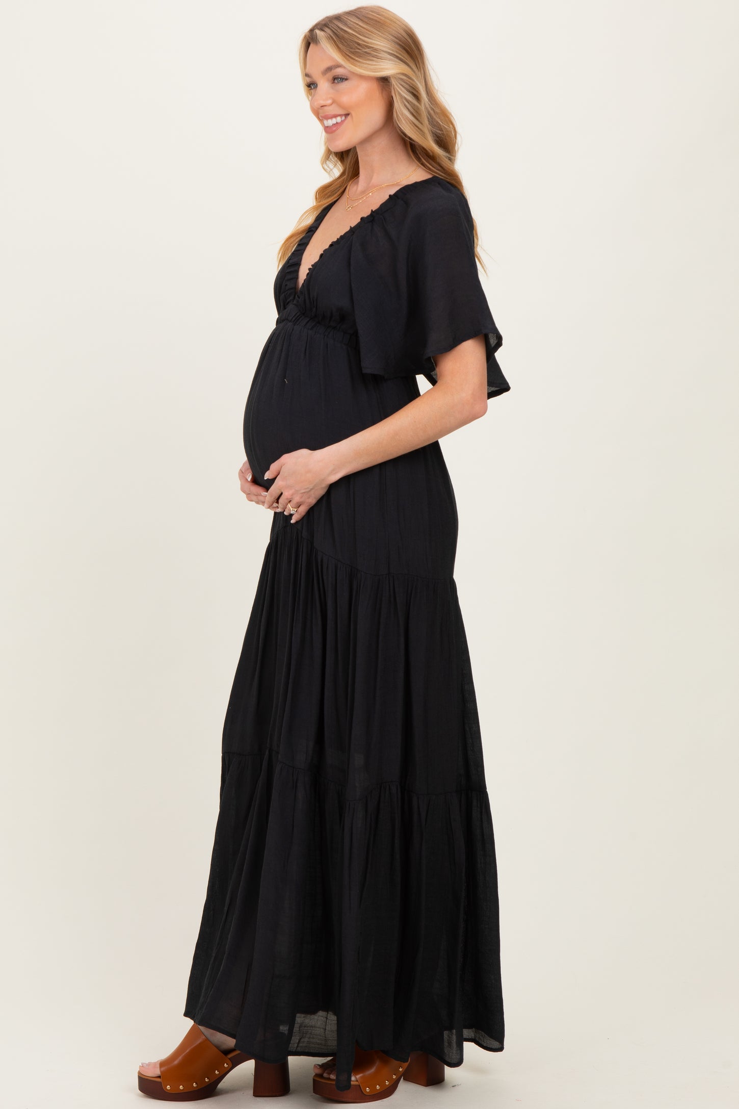 woman wearing a black maxi maternity dress with flutter sleeves and a visible baby bump