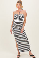 woman wearing a black and white striped maternity maxi dress with a halter neck and a side slit, showcasing her baby bump