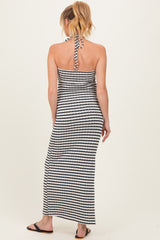 woman wearing a black and white striped maternity maxi dress with a halter neck and open back, showing no baby bump