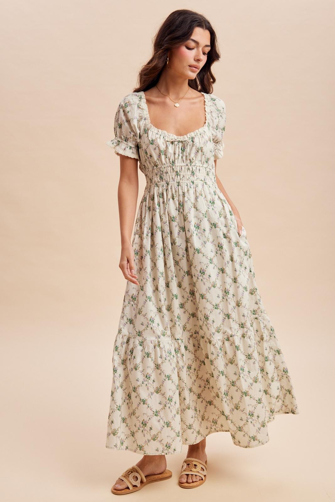 woman wearing a cream floral maxi dress with puff sleeves and a smocked bodice, styled with sandals and relaxed hair