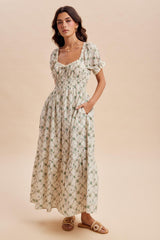 woman wearing a cream floral maxi dress with puff sleeves and pockets, standing against a neutral background