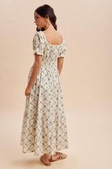 woman wearing a floral print maxi dress with puff sleeves and a smocked waist, standing against a neutral background
