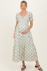 woman wearing a floral printed maternity maxi dress with puff sleeves and holding her baby bump