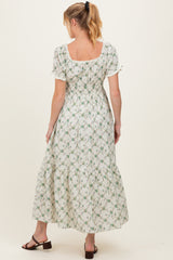 woman wearing a floral print maternity maxi dress with puff sleeves and a smocked back, showing her baby bump