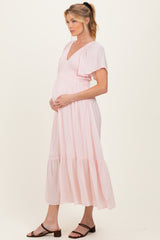 woman wearing a pink maternity maxi dress with flutter sleeves and a baby bump