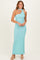 woman wearing a light blue one-shoulder maxi dress with a choker neckline and high heels