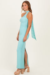 woman wearing a light blue sleeveless maxi dress with a side slit and a draped scarf detail