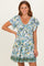 woman wearing a short white floral print dress with puffed sleeves and a gathered waist