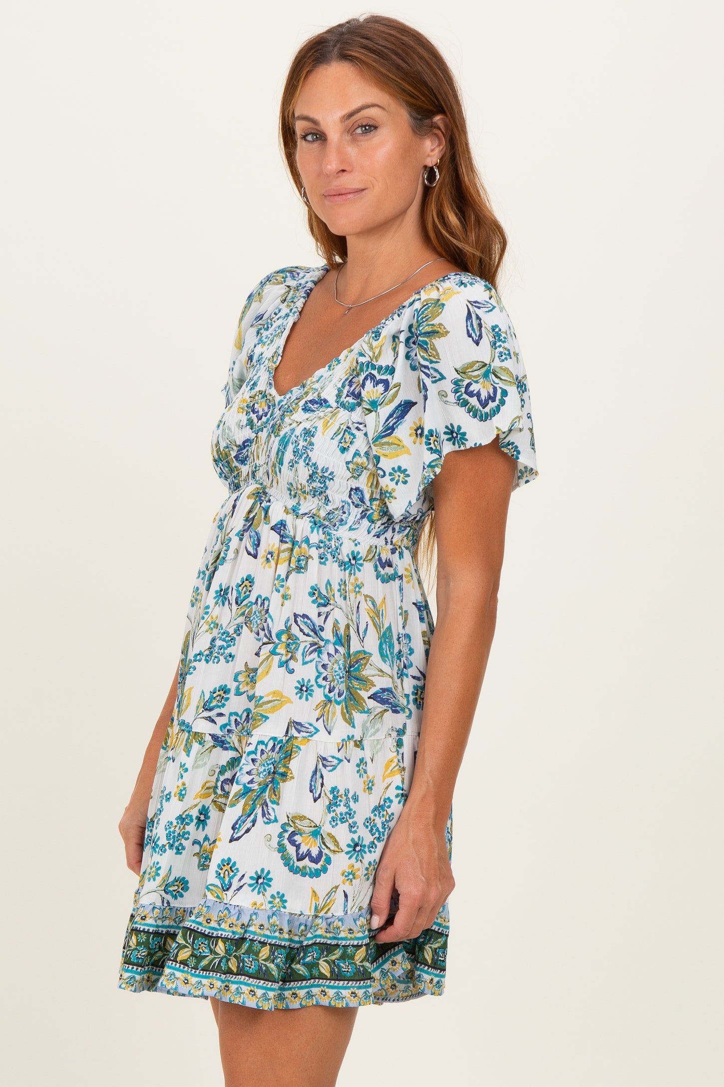 woman wearing a white floral print short dress with a smocked waist and short sleeves