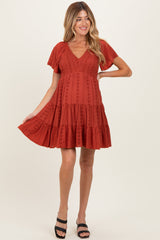 woman wearing a rust-colored short sleeve maternity dress with a tiered skirt and a baby bump visible