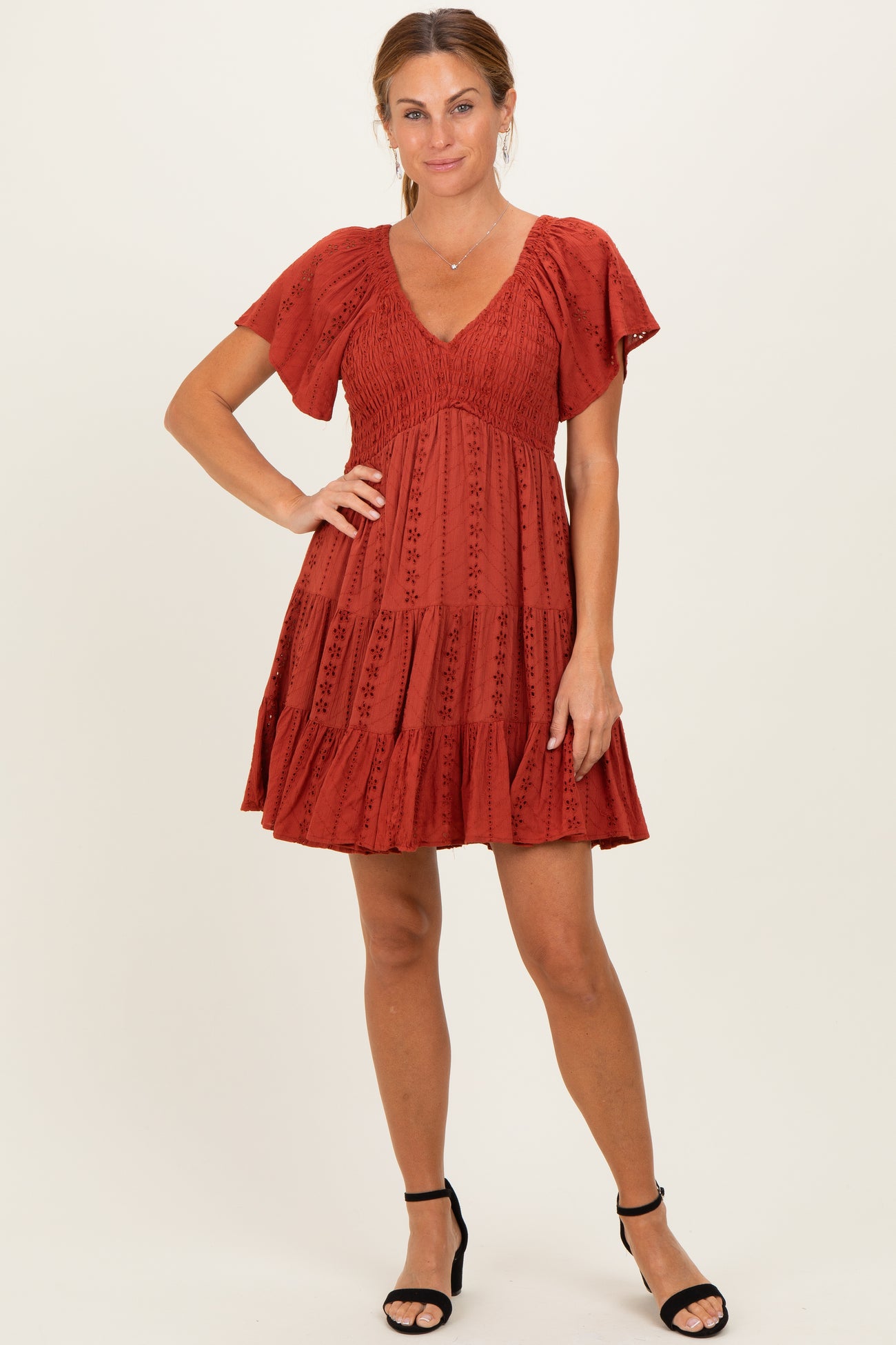 woman wearing a rust-colored short dress with flutter sleeves and a tiered skirt