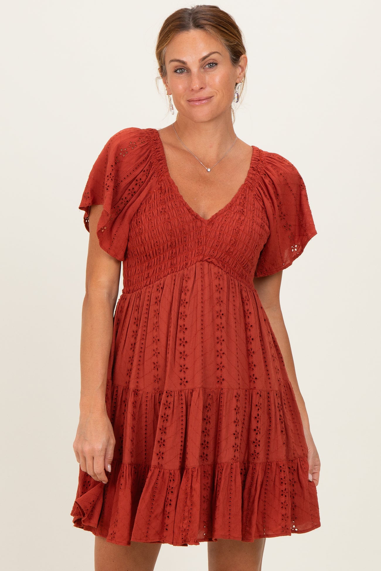 woman wearing a terracotta short sleeve tiered summer dress with a smocked bodice and delicate floral details