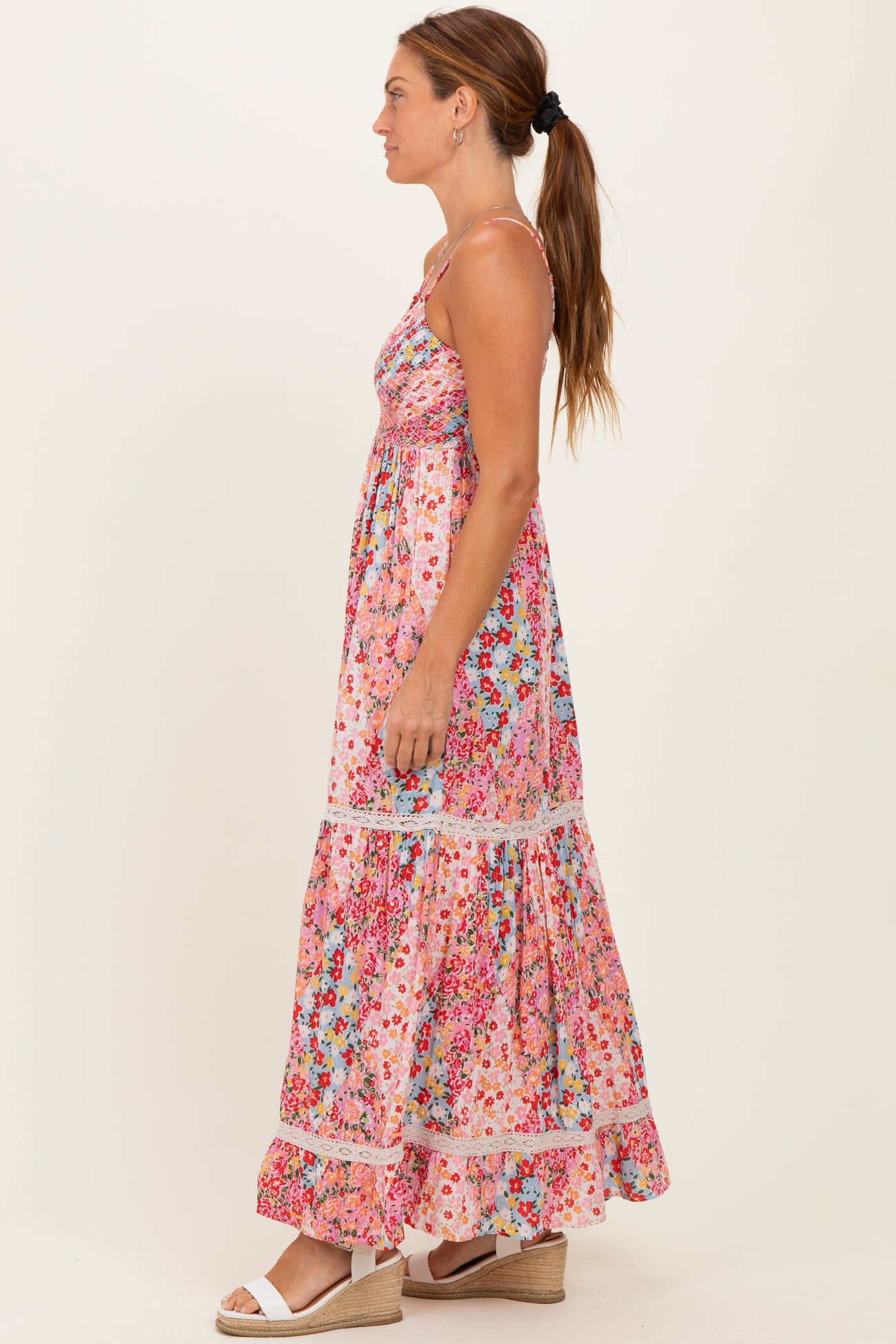 woman wearing a pink floral maxi dress with tiered ruffles and spaghetti straps, standing sideways against a plain background