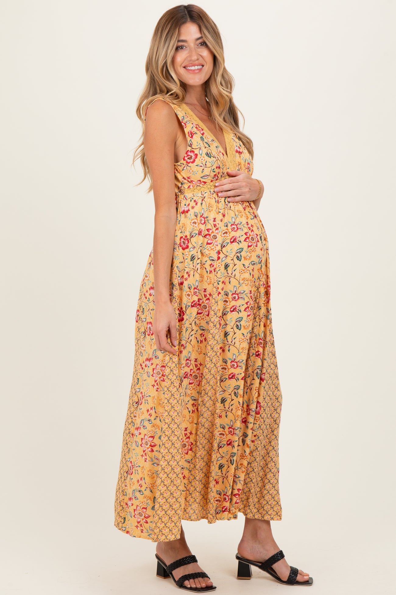 woman wearing a yellow floral maternity maxi dress and holding her baby bump