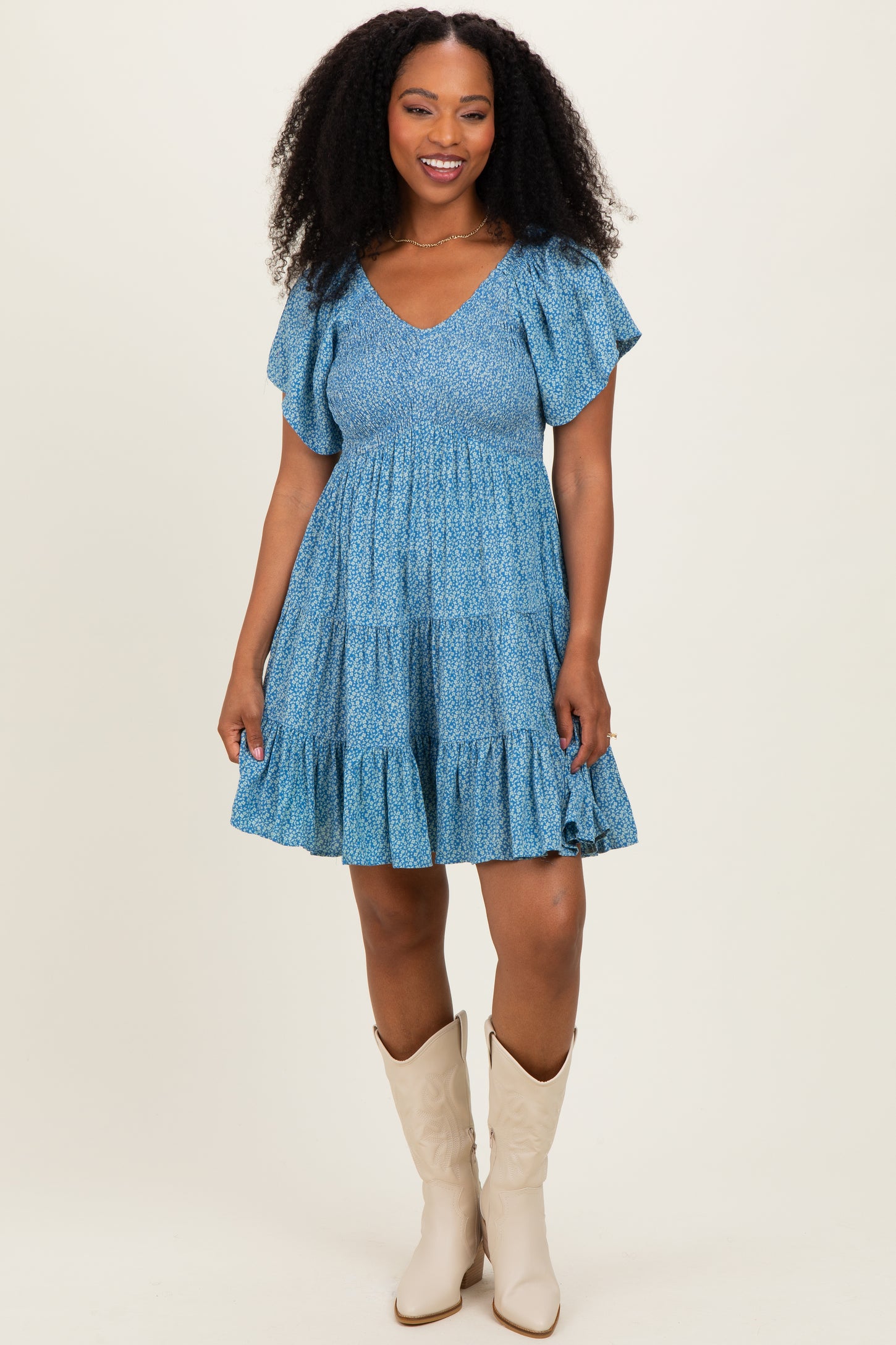 woman wearing a blue tiered sundress with ruffled sleeves and cowboy boots