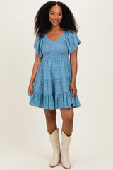 woman wearing a blue tiered sundress with ruffled sleeves and cowboy boots