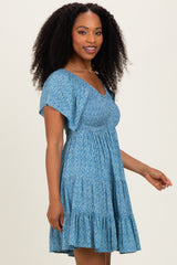 woman wearing a short blue floral dress with a v-neckline and ruffled hem