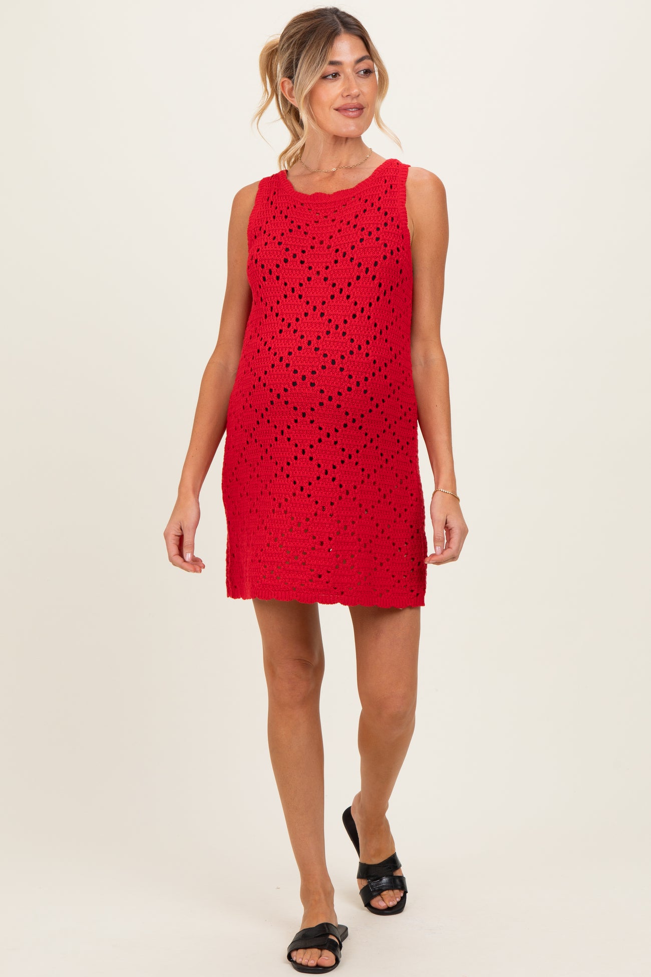 woman wearing a red sleeveless maternity dress with a perforated design and a visible baby bump